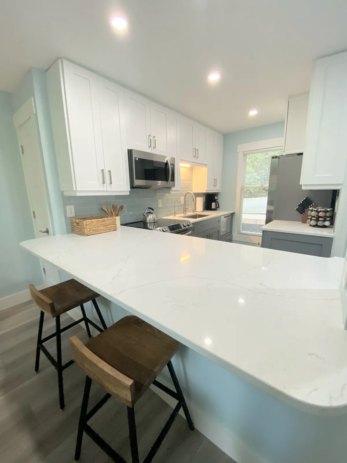 A modern, fully equipped kitchen with a central island, white cabinetry, and stainless steel appliances. The kitchen design encourages socializing and group meal preparation, with plenty of countertop space for cooking or casual gatherings.