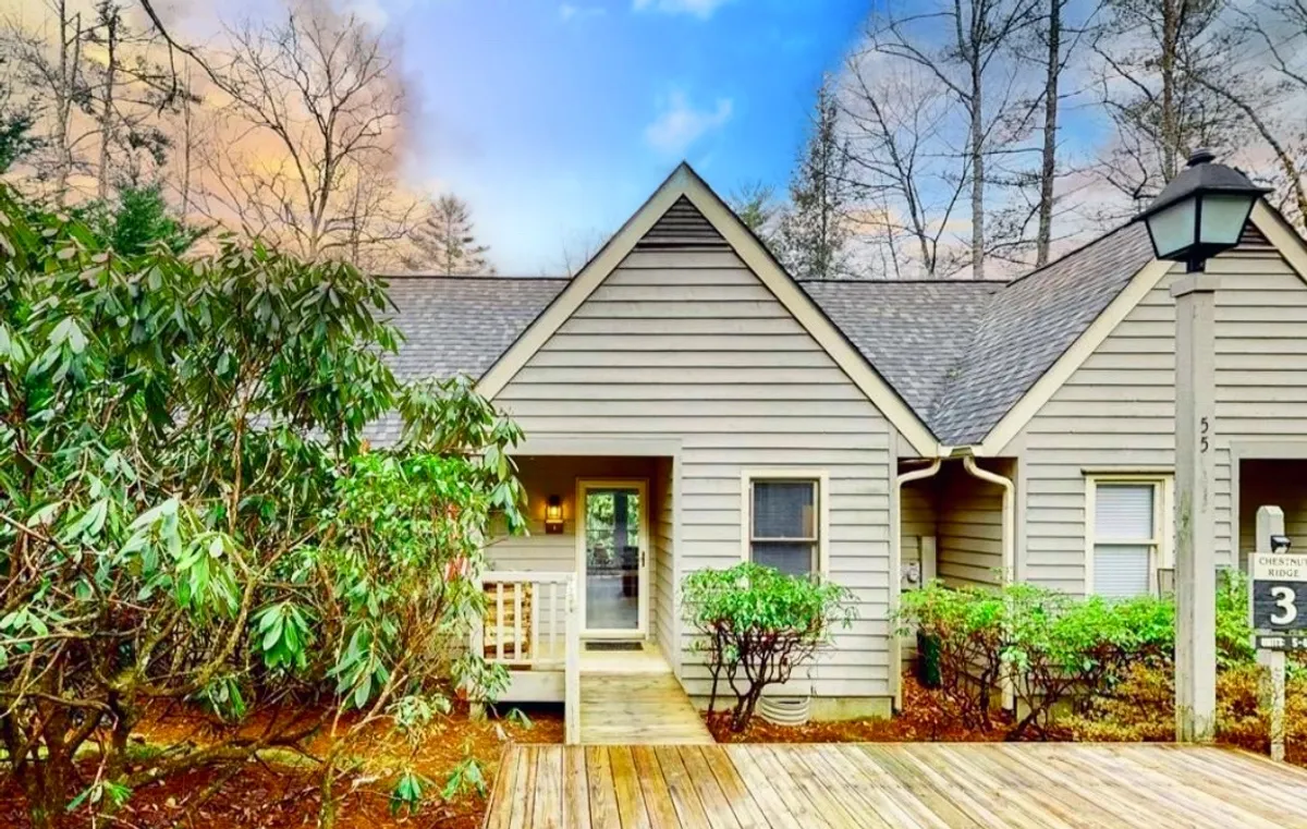 A private wooden deck set just outside the front door, surrounded by lush shrubs and greenery. The deck is bathed in natural light, offering tranquil views into the surrounding woodland—a perfect spot for relaxing, morning yoga, or enjoying a drink as the sun sets.